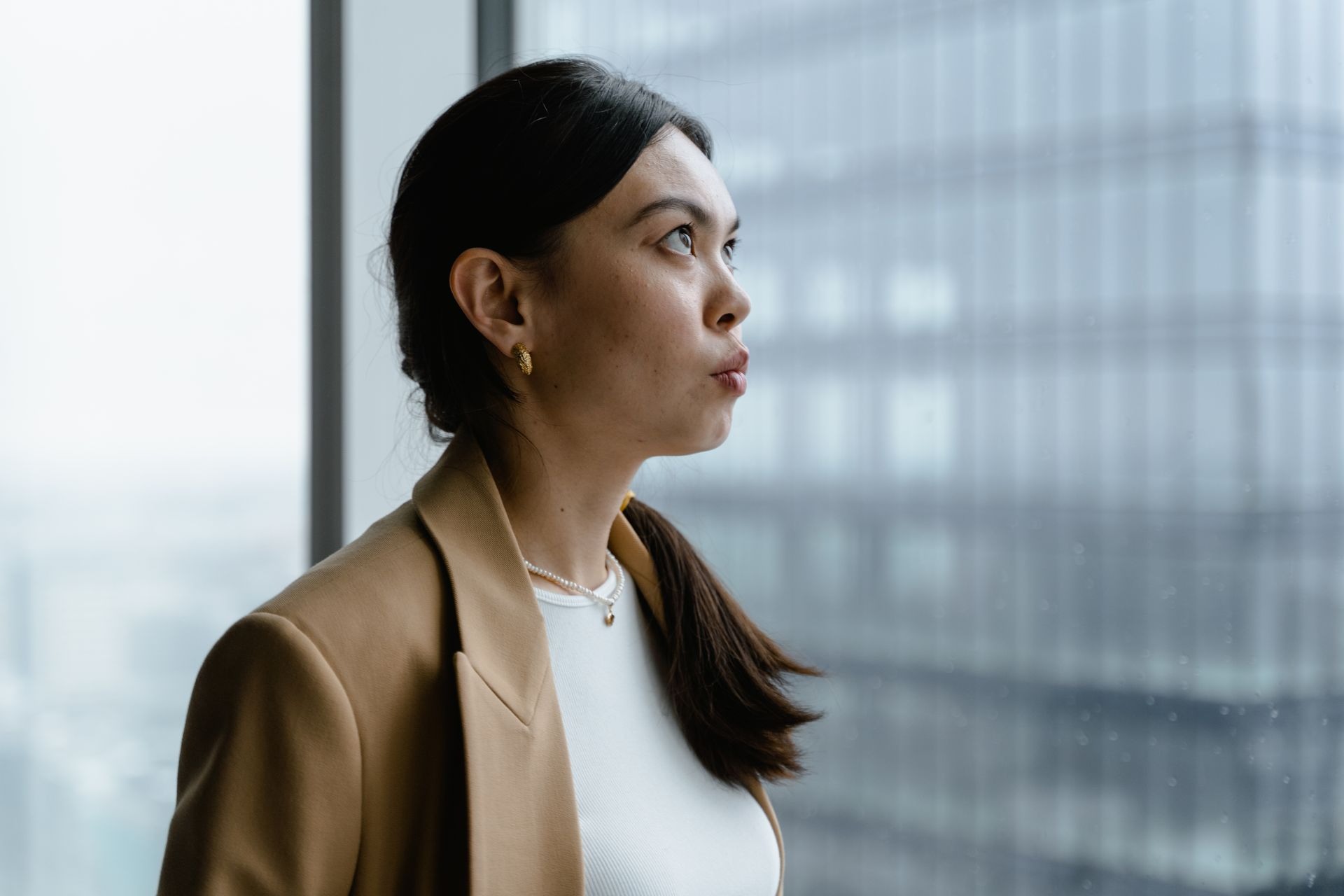 professional woman with concerned expression looking up out sky rise building