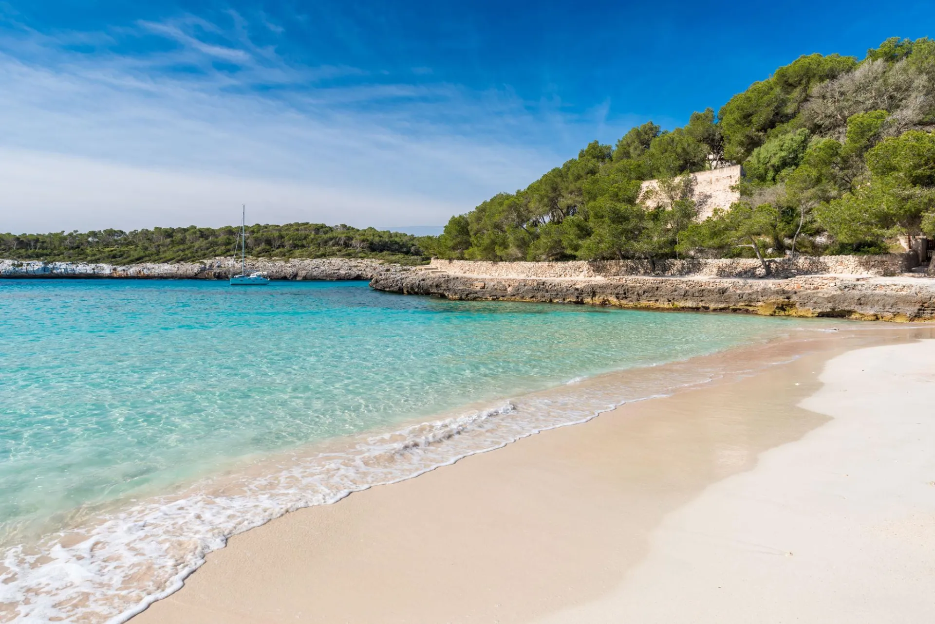 Cala Mondragó beach in Mallorca with turquoise water, sandy shore and pine trees in Mondragó Natural Park