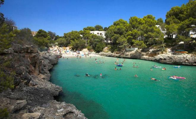 Cala Serena beach in Mallorca with clear turquoise water, rocks and a small sandy cove