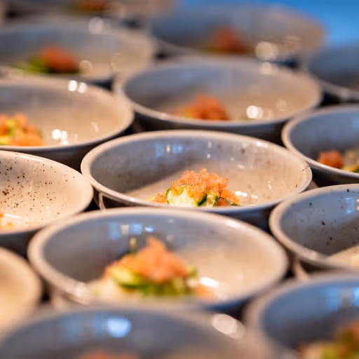 Små keramikskålar fyllda med små portioner mat, toppade med orange garnish.