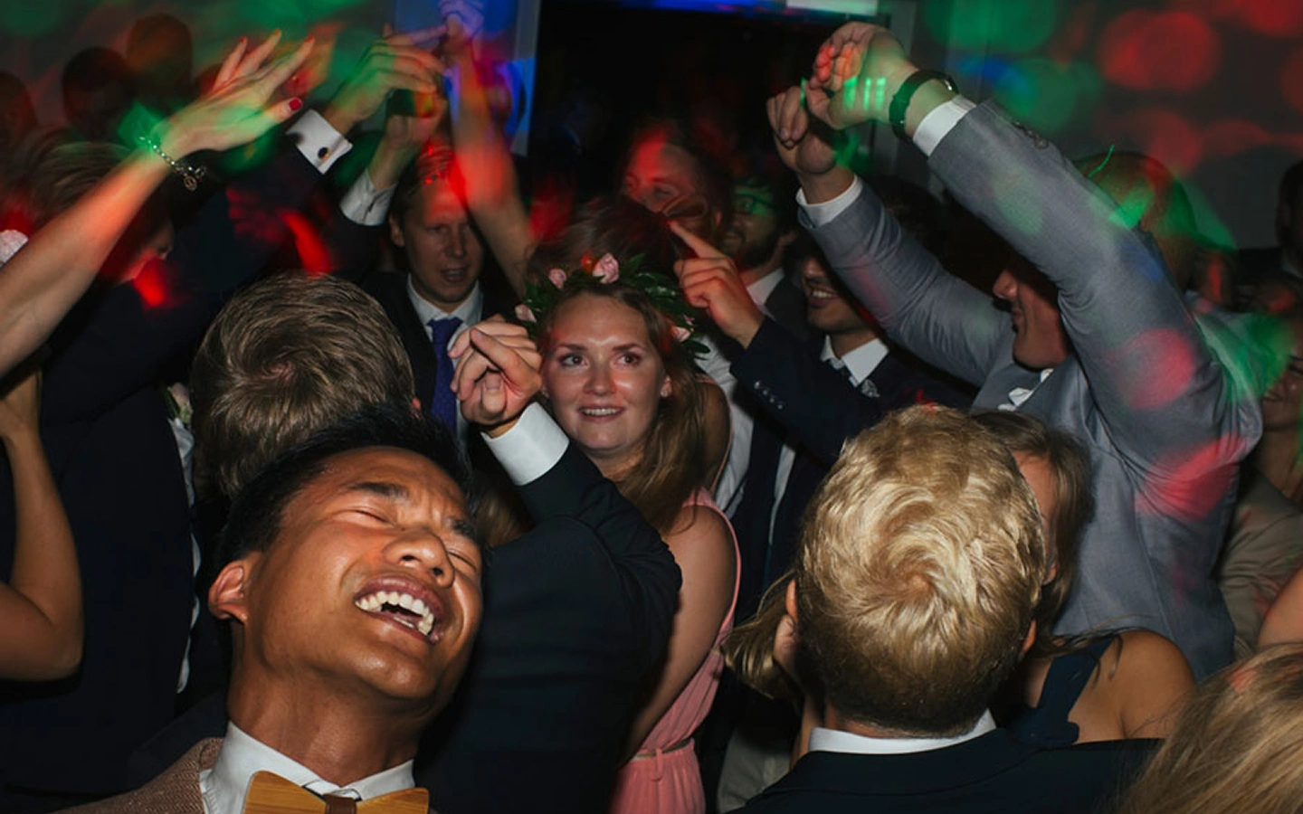 Folk dansar glatt under en fest med färgglada ljuseffekter och formella kläder.