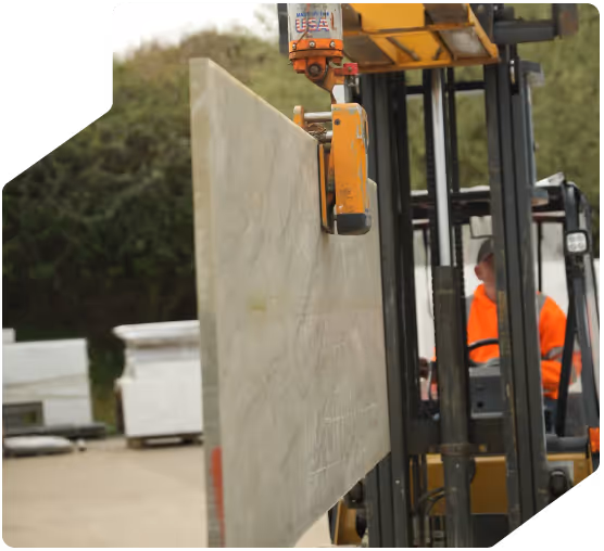 Worker using a forklift truck to lift a slab of worktop