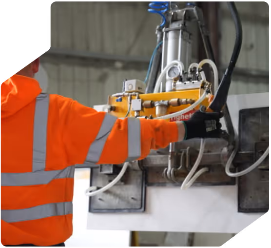 Worker using a hydraulic crane to lift a slab of stone worktop
