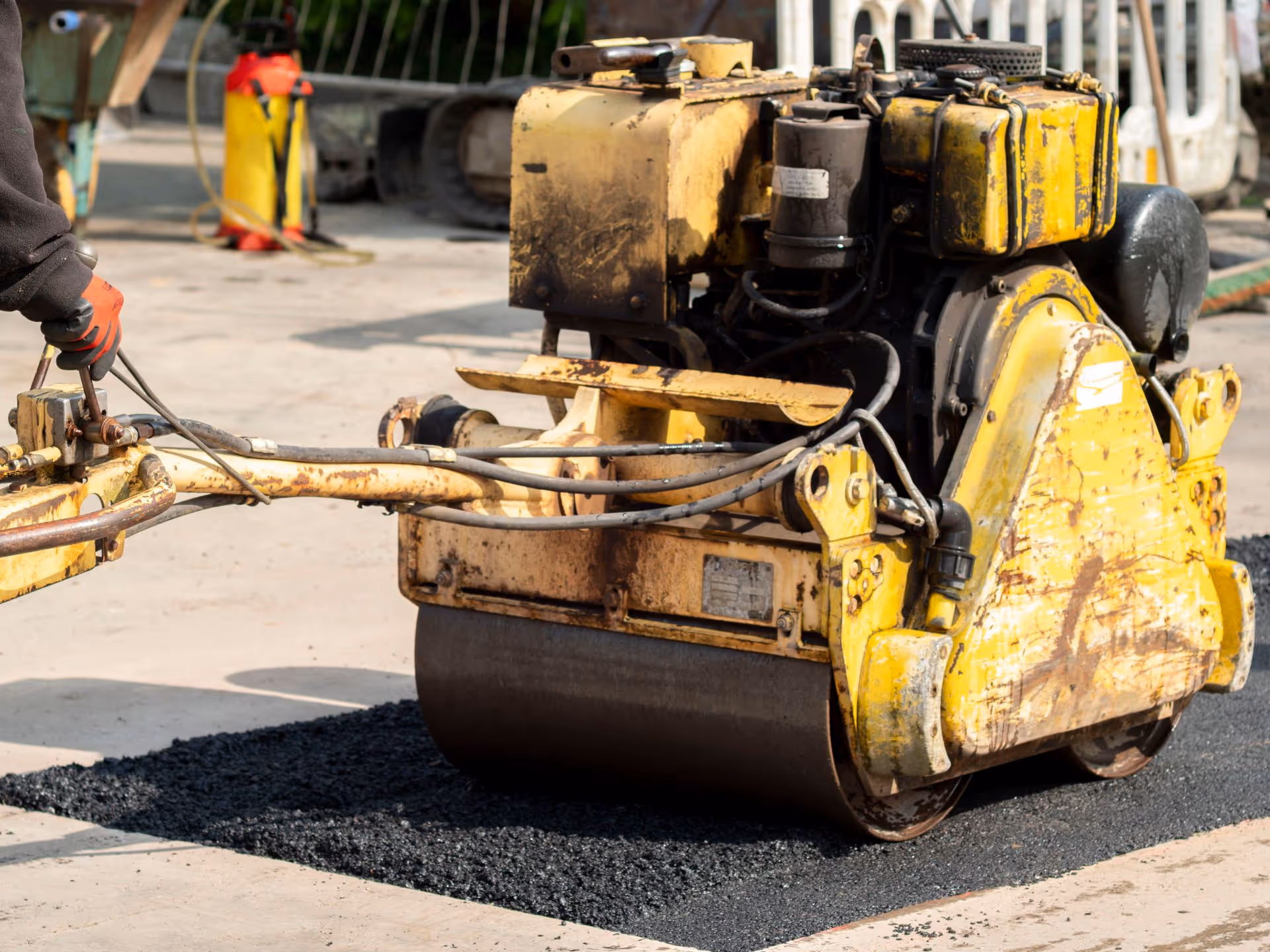 Worker using packer on tarmac