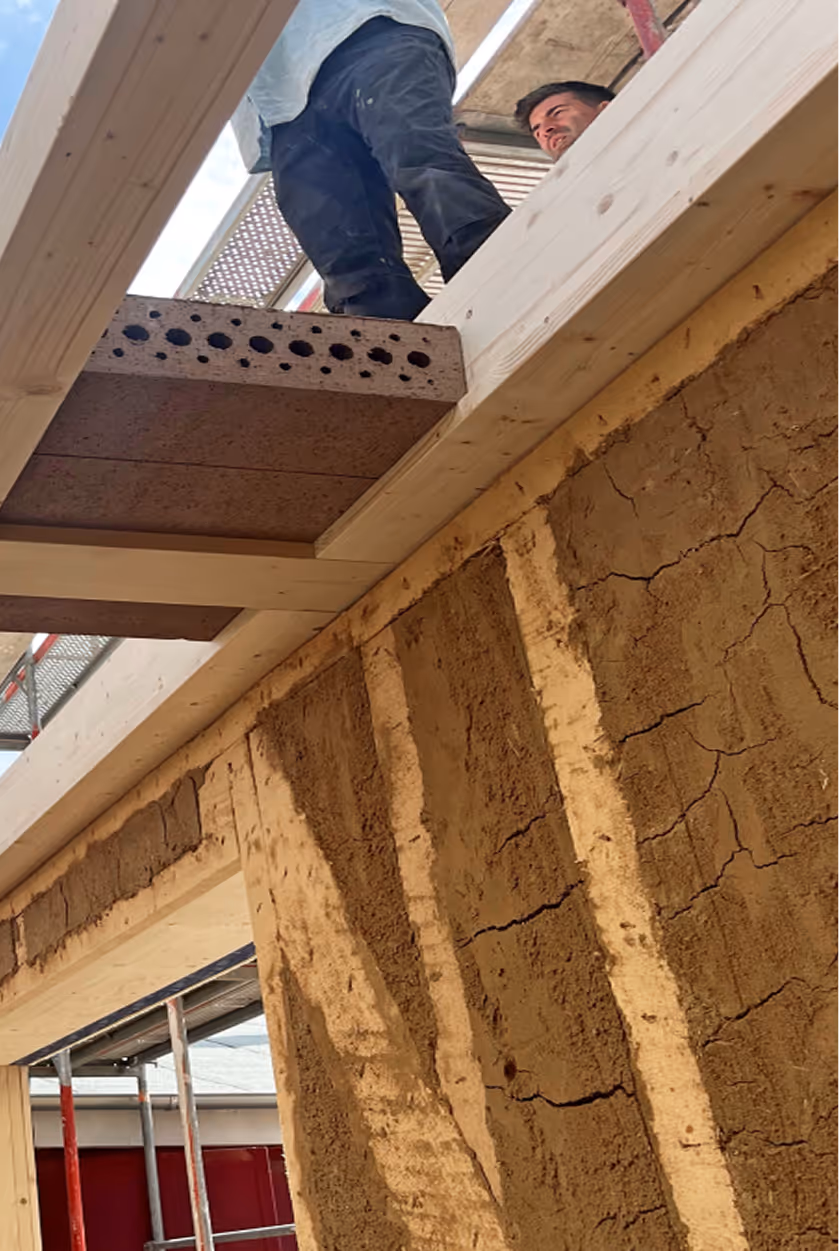 Einbau von Holzfaserdämmung zwischen Holzständerkonstruktion während des Rohbaus des Holz-Lehm-Hauses