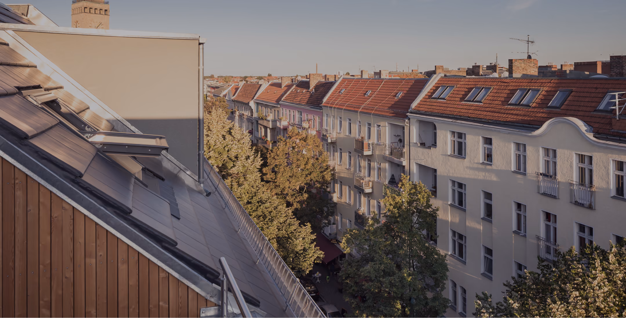 Blick von der neuen Dachterrasse über die Berliner Altbau-Dachlandschaft mit Holzfassade der Aufstockung im Vordergrund