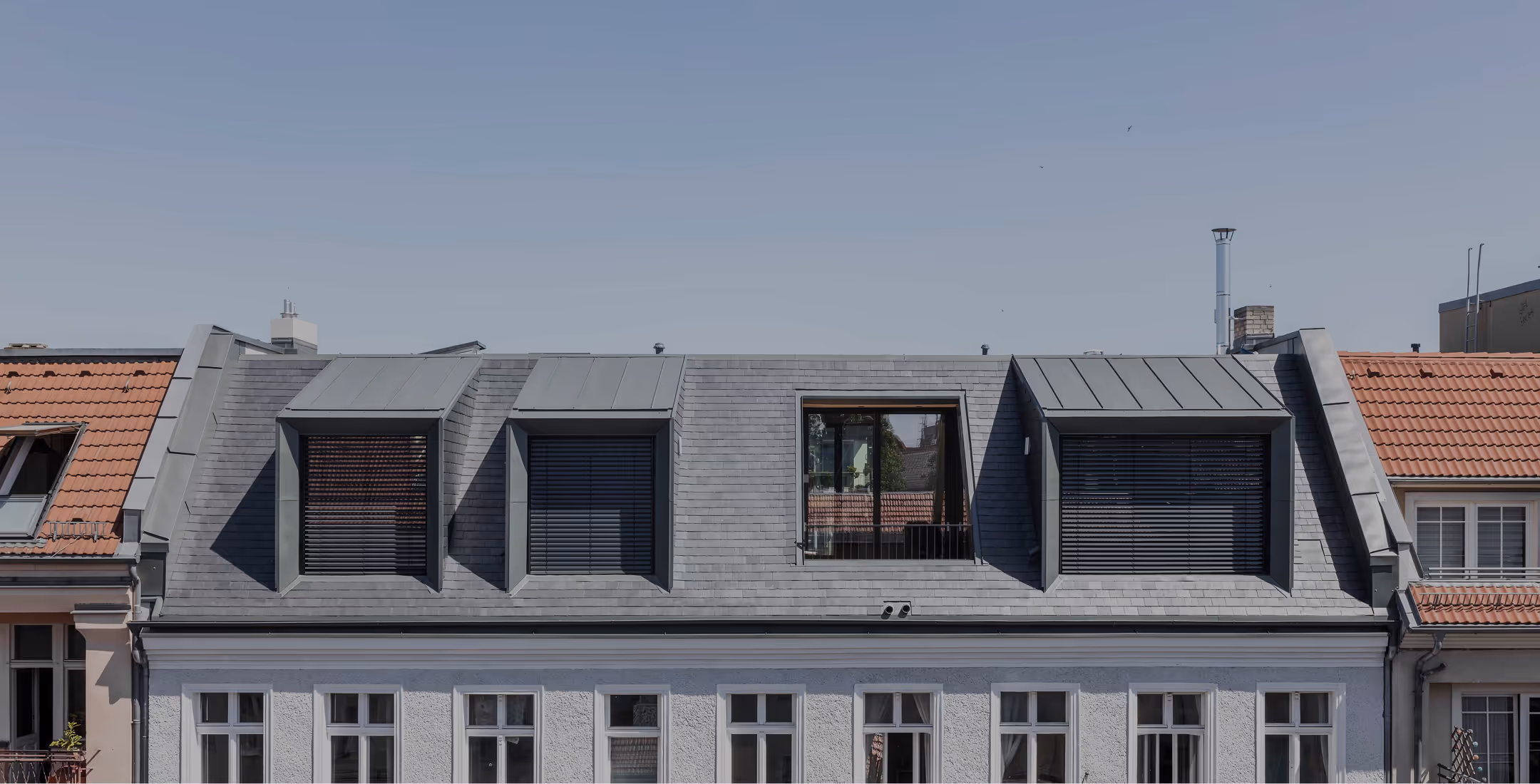 Moderner Penthouse-Dachaufbau mit Zinkfassade über historischer Berliner Altbau-Dachlandschaft mit Backsteindächern