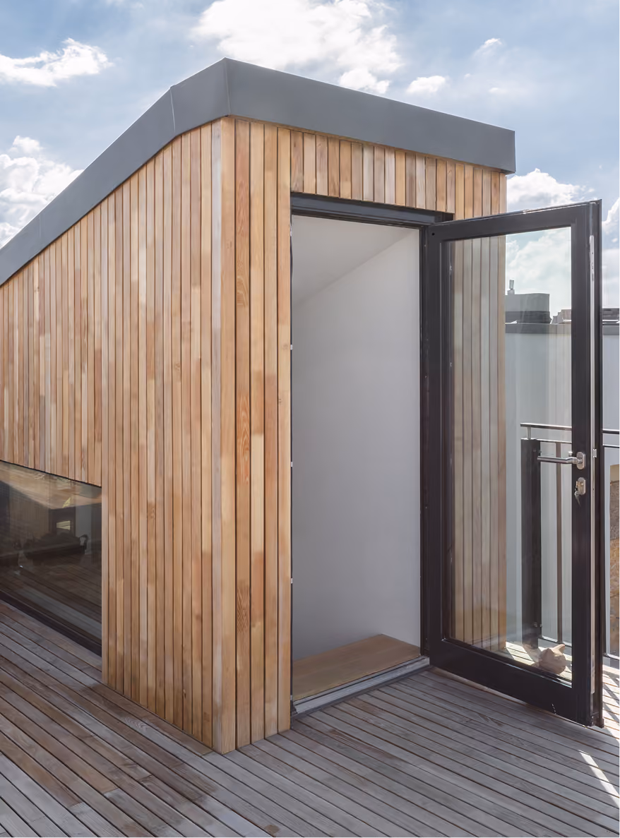 Holzverkleideter Aufbau auf der Dachterrasse des Penthouse mit Glastür und umlaufender Holzdielen-Terrasse