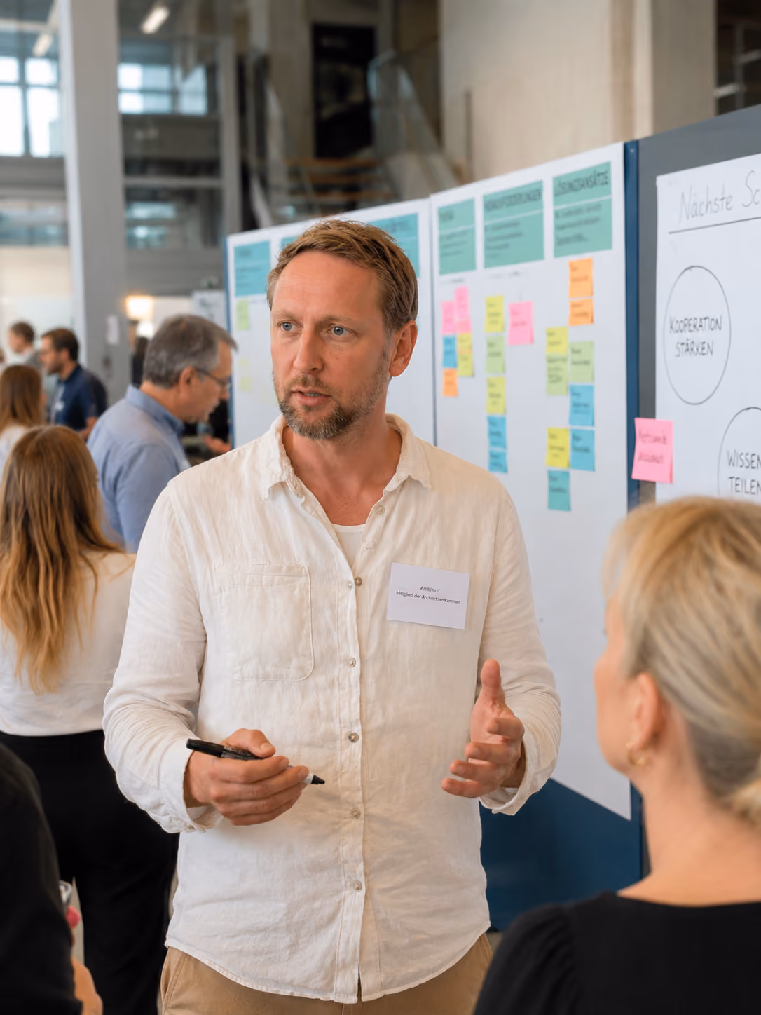 Architekt Daniel Boepple im Gespräch auf einer Fachveranstaltung vor einem Moderationswand mit Post-its