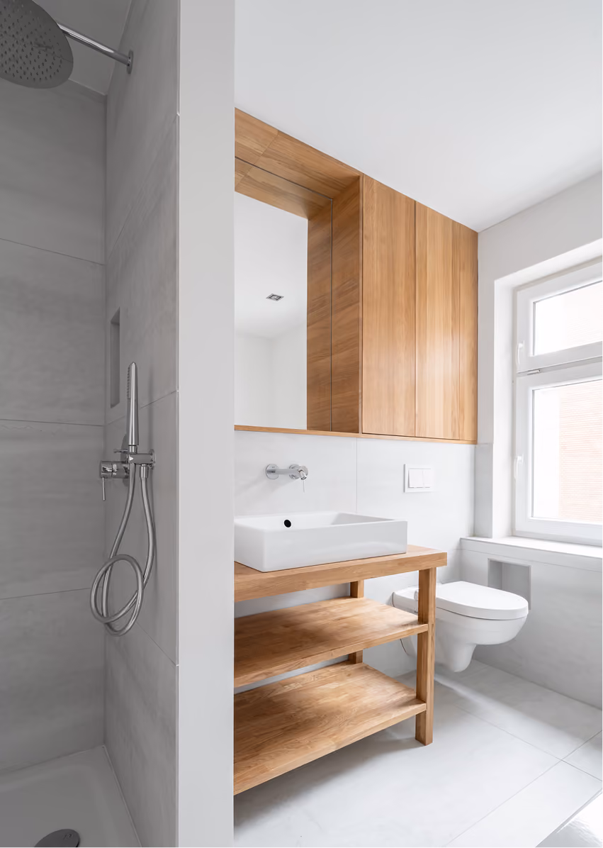 Badezimmer der Maisonette mit offenem Holzregal als Waschtischunterbau, weißem Hängeschrank und Fliesen in Grau