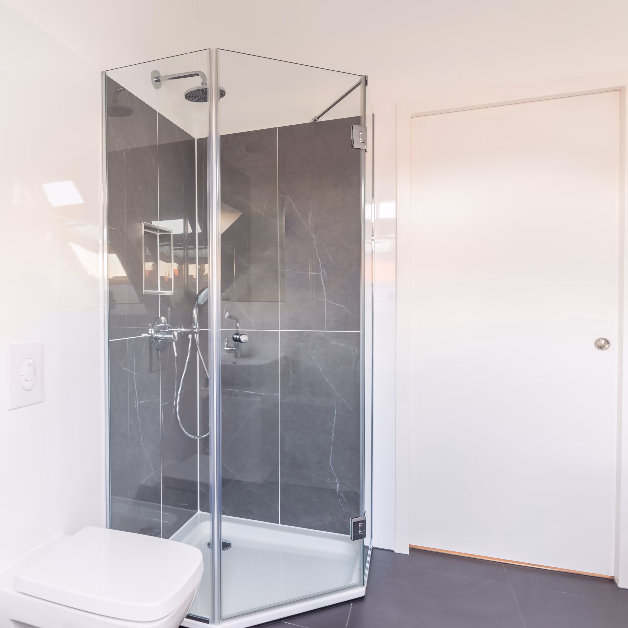 Begehbare Dusche mit Glaswänden in der Dachaufstockung, Fliesen in Betonoptik und bodengleicher Duschwanne