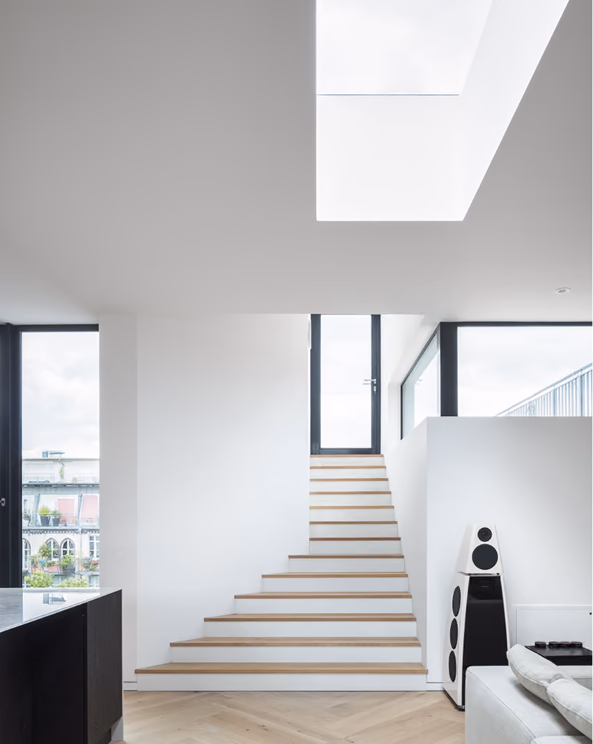 Offene Treppe im Penthouse unter großem Deckenoberlicht, Blick in lichtdurchfluteten Wohnbereich mit Fensterfront