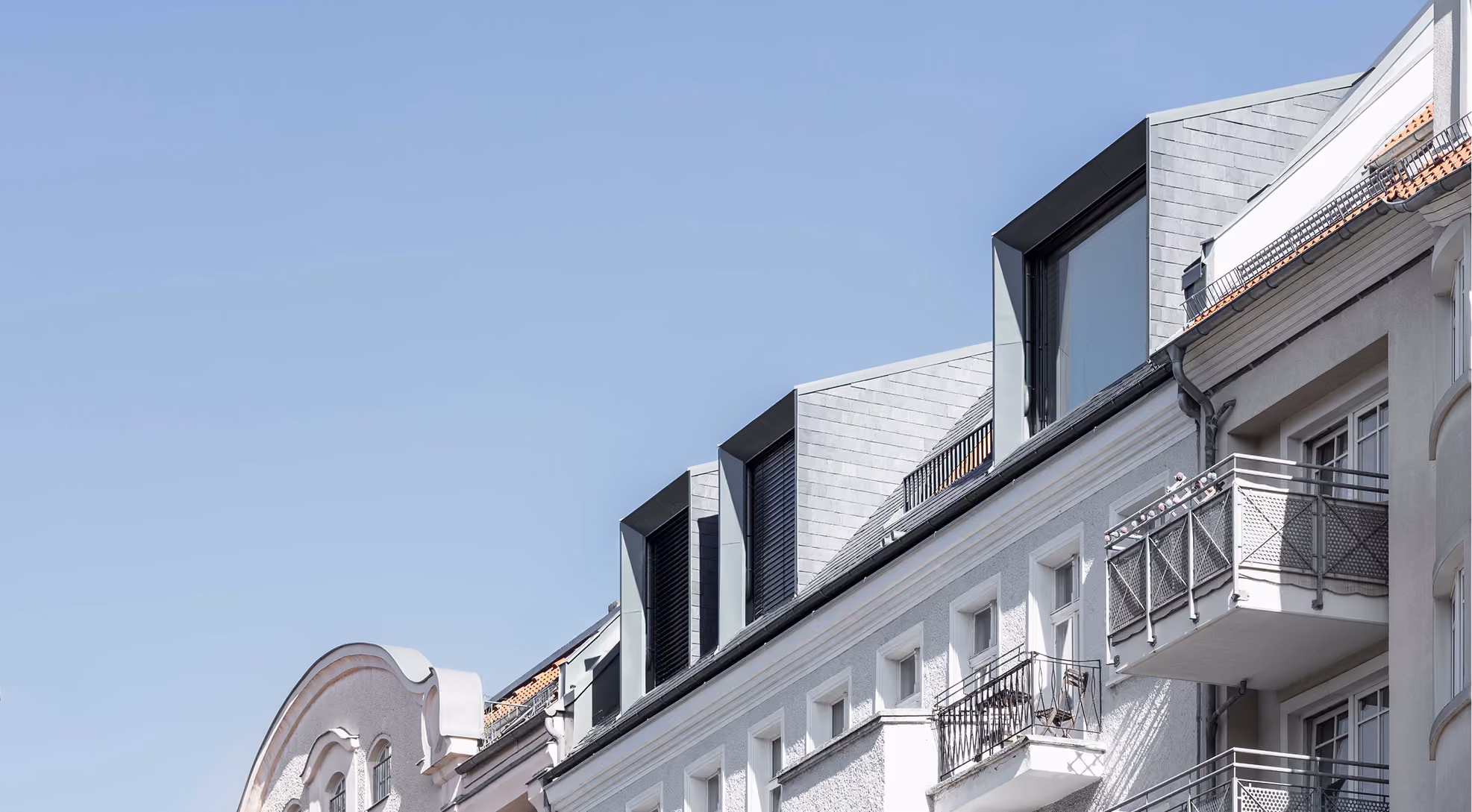Straßenansicht des Penthouse-Dachaufbaus mit Zinkfassade über klassizistischer Altbaufassade mit Balkonen