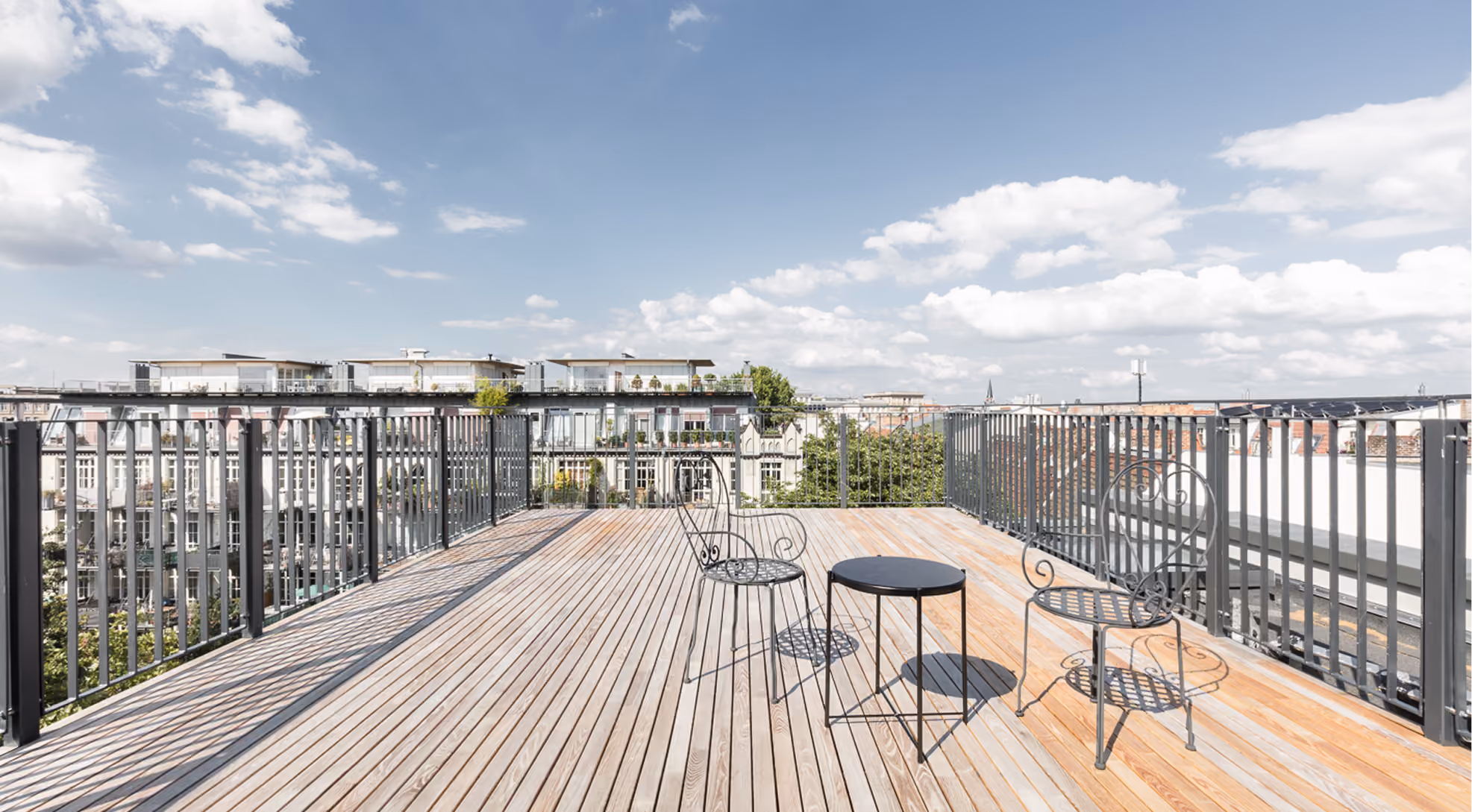 Dachterrasse des Penthouse mit Holzdielenboden, Sitzgruppe und Panoramablick über die Berliner Dachlandschaft