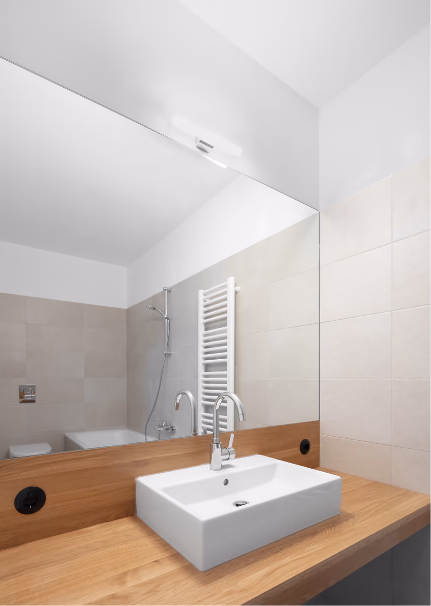 Badezimmer der Remise mit weißem Waschbecken auf Holzunterbau und kleinem Deckenfenster