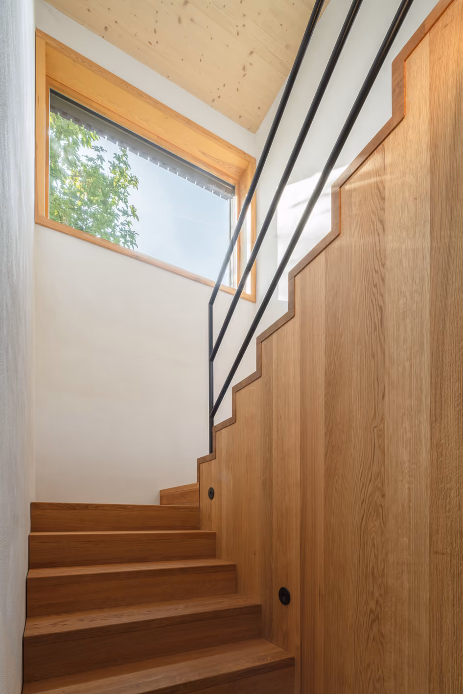Helle Holztreppe im Holz-Lehm-Haus mit schmalem Stahlgeländer und großem Oberlicht