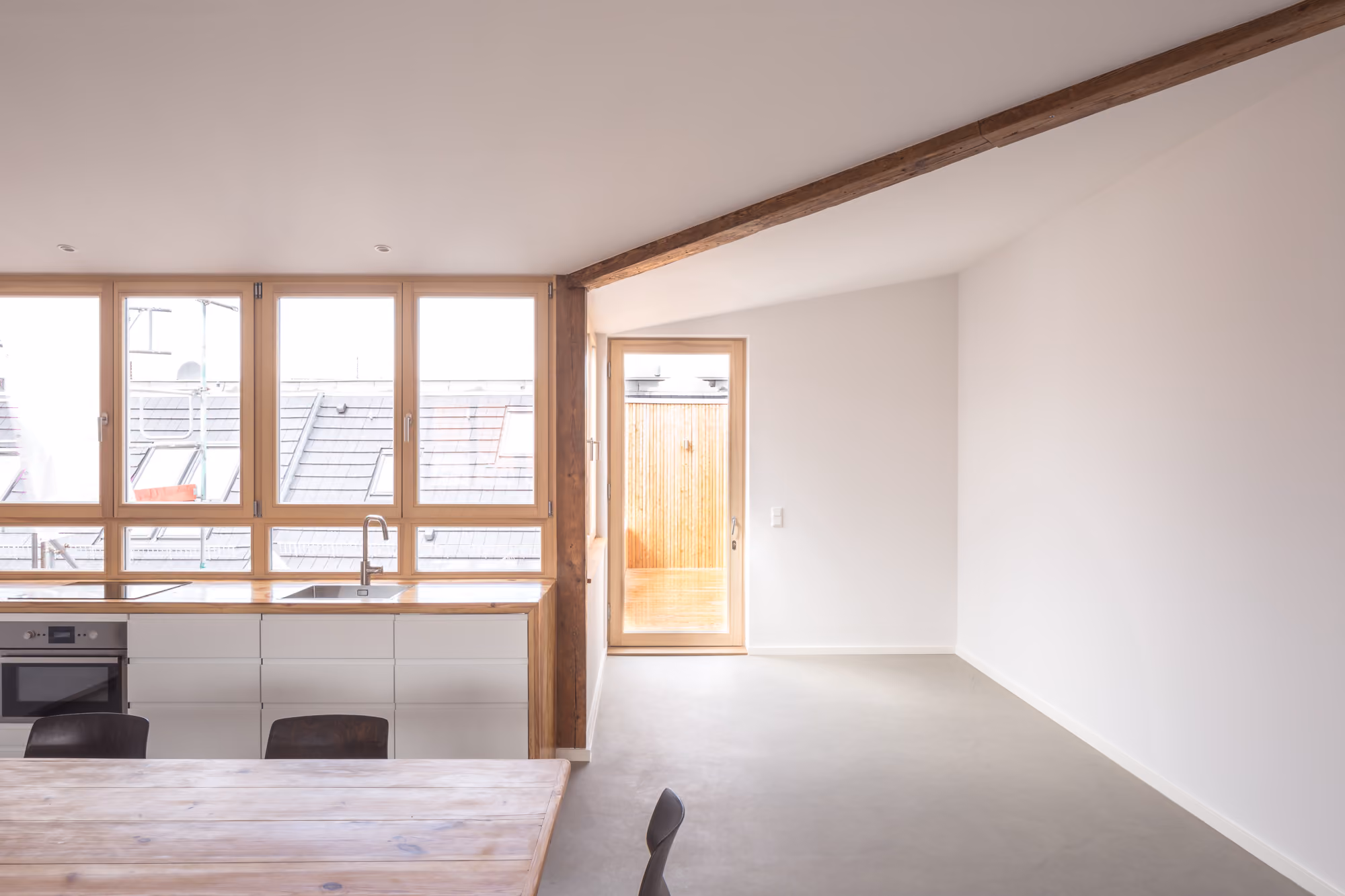 Offene Küche der Dachaufstockung mit großformatigen Holzfenstern, Blick über die Berliner Dächer und Terrassentür aus Holz