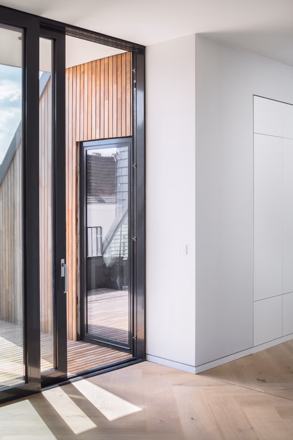 Eingangsbereich des Berliner Penthouse mit schwarzem Stahlrahmen, Holzeinsatz und Blick in den hellen Innenraum