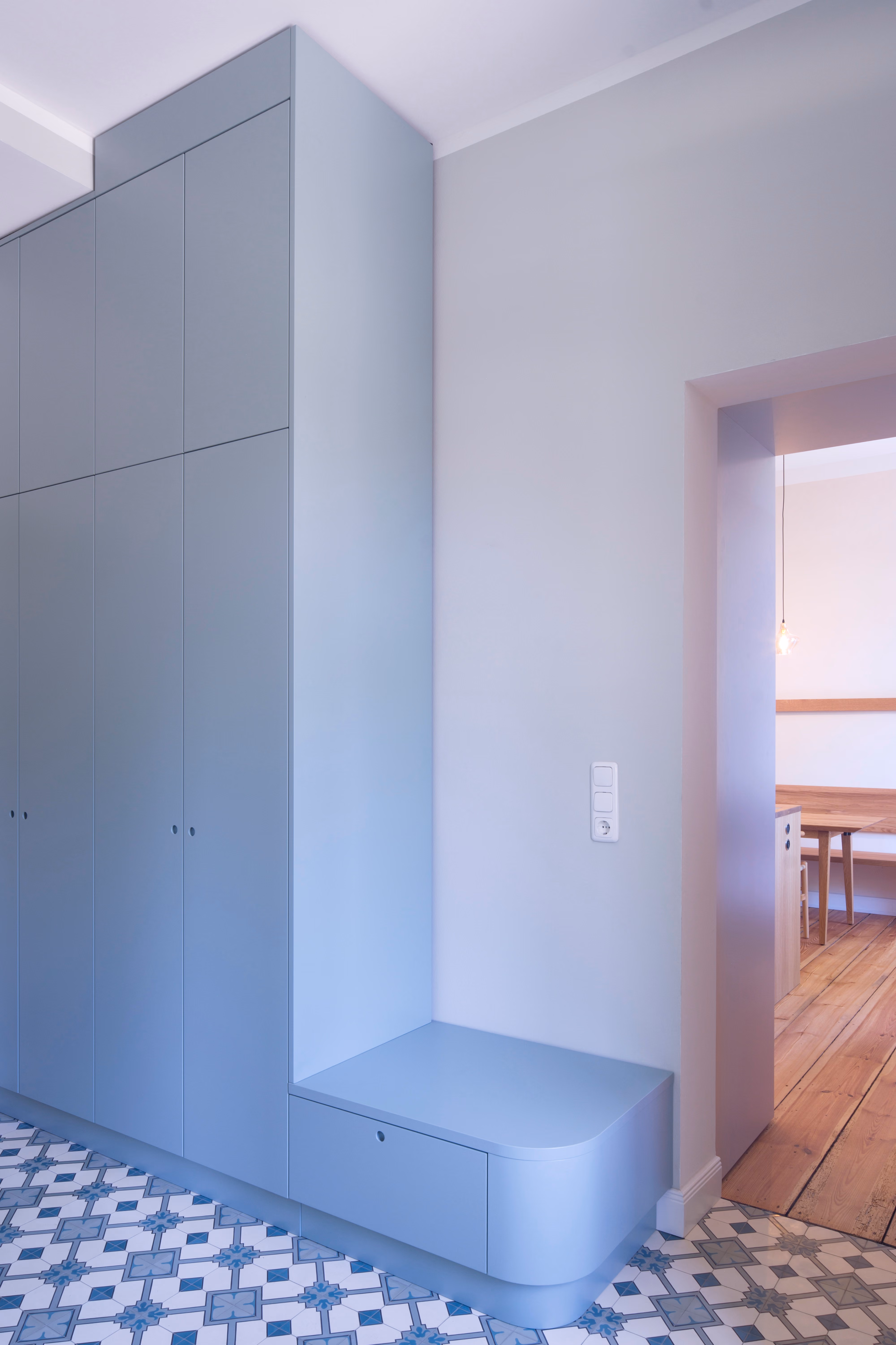 Raumhoher Einbauschrank in Taubenblau mit integrierter Sitzbank im Flur der Altbauwohnung Schwerin, Mosaikfliesenboden
