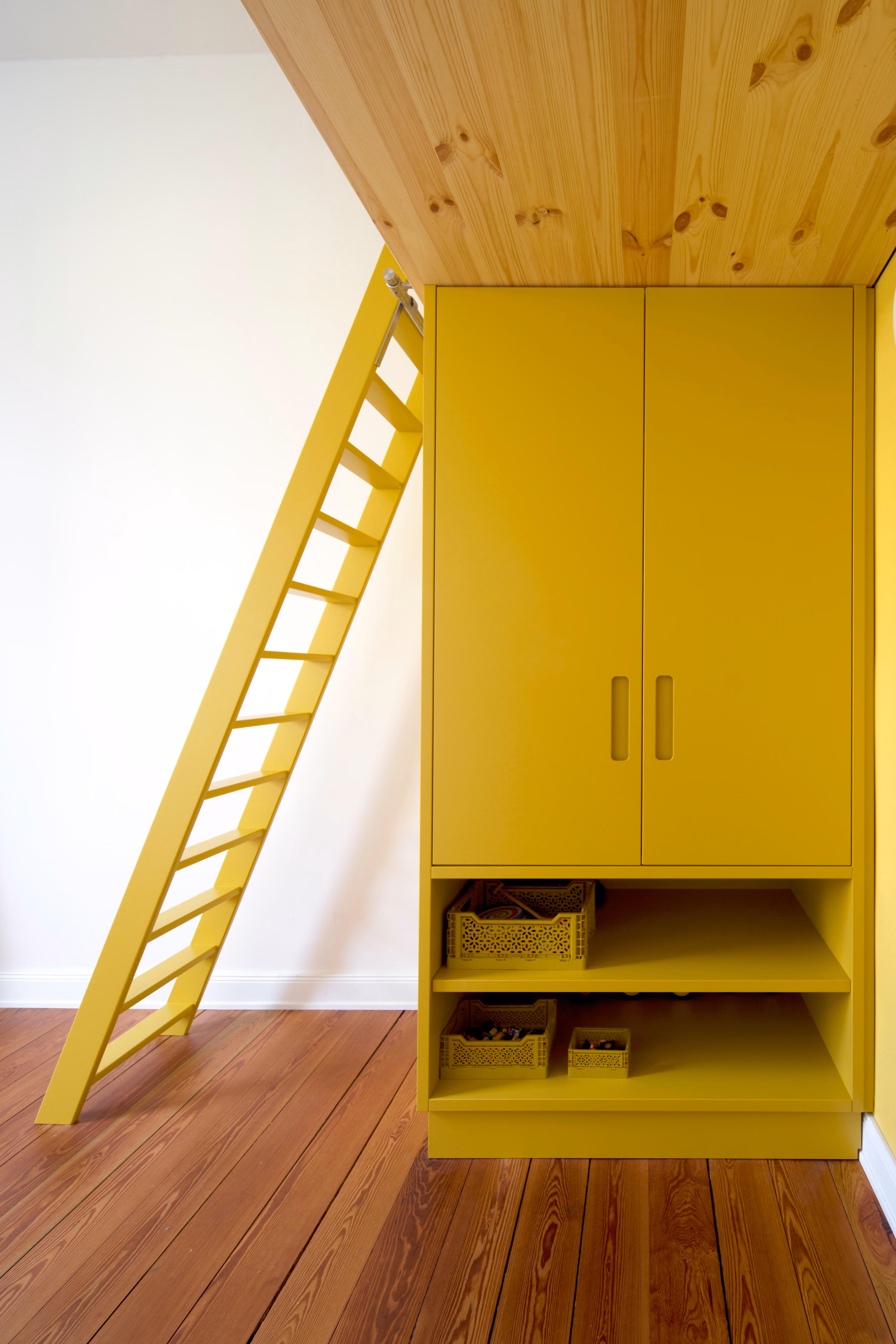 Gelber Einbauschrank mit Schuhfächern unter der Hochbettebene im Kinderzimmer der Altbauwohnung Schwerin, sichtbare Holzdecke