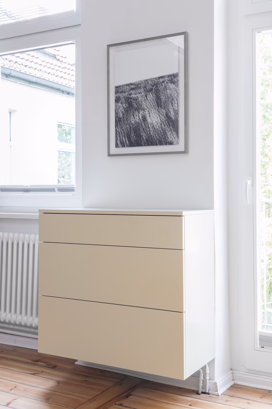 Maßgefertigte Kommode aus hellem Holz mit Lamellenfronten in der Stadtwohnung, Altbaufenster im Hintergrund