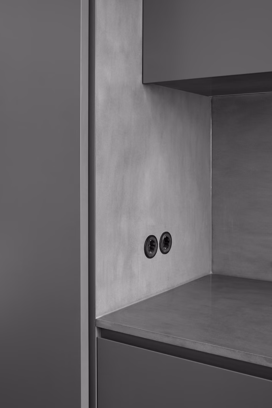 Detailaufnahme der anthrazitfarbenen Küchenfront mit versenkter Steckdose und Betonoptik-Arbeitsplatte