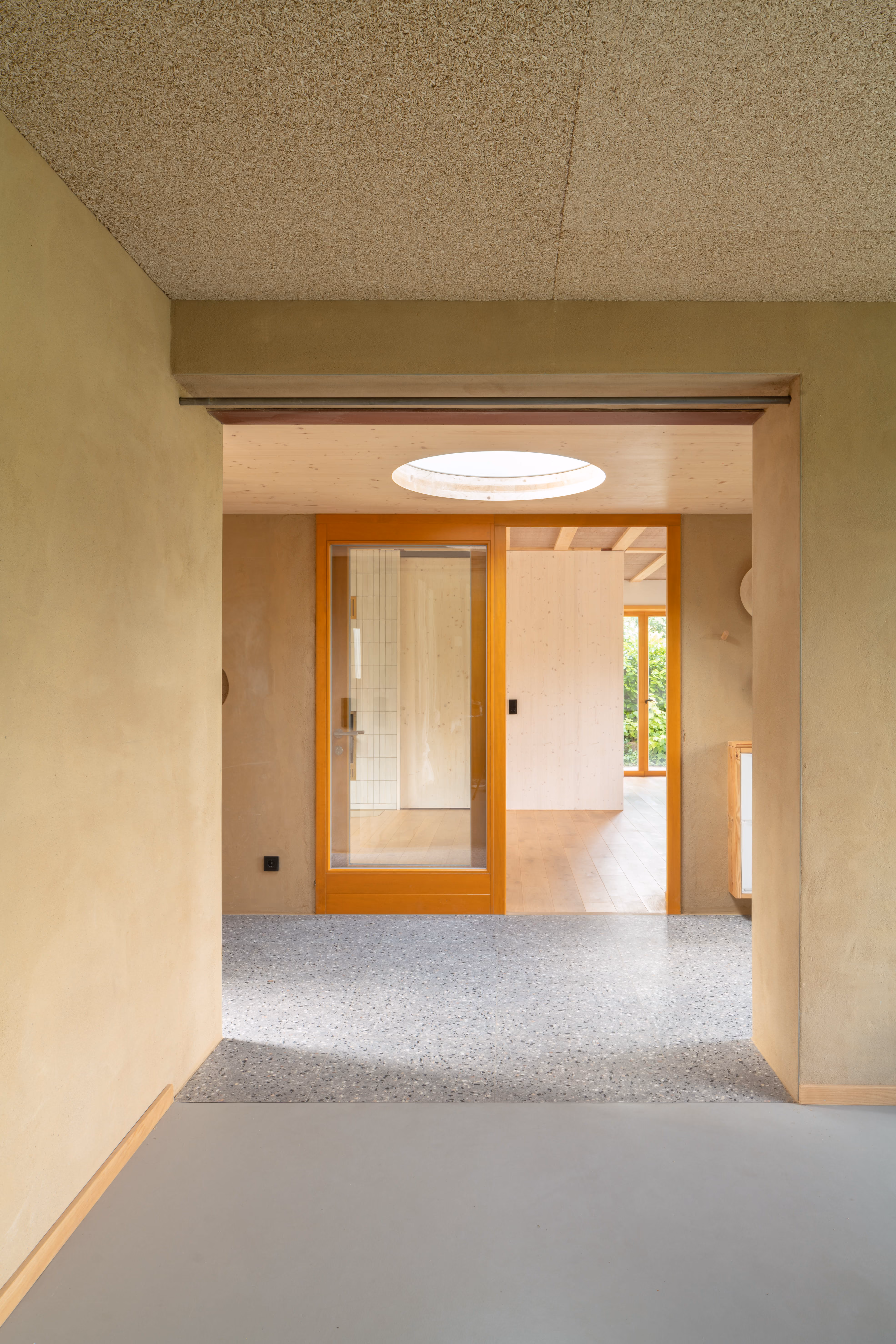 Heller Flur mit Sichtbeton und Holzelementen, Holz-Stroh-Lehm-Haus Daniel Boepple Architekt