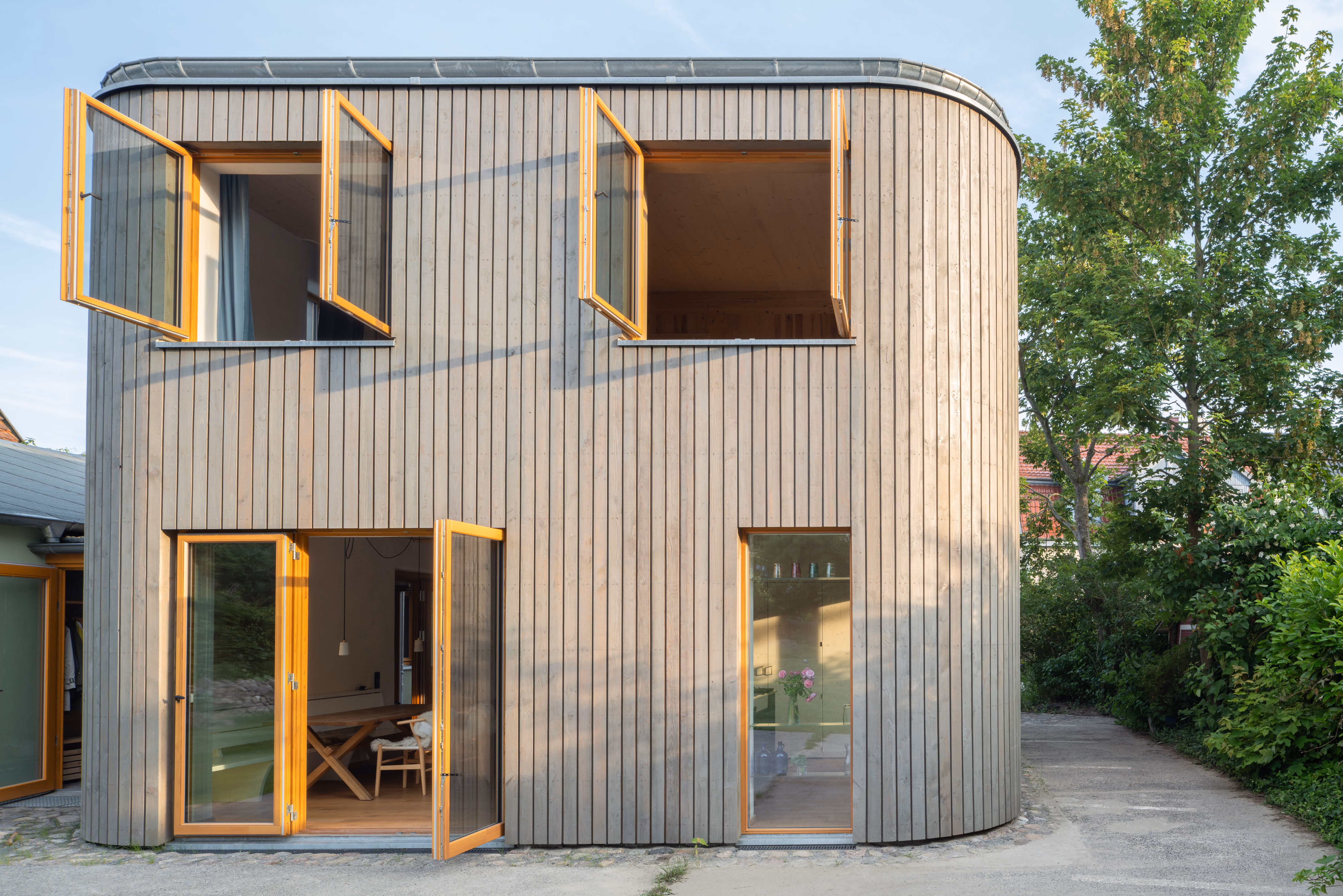 Außenansicht des Holz-Stroh-Lehm-Hauses von Daniel Boepple Architekt mit Holzfassade und Garten