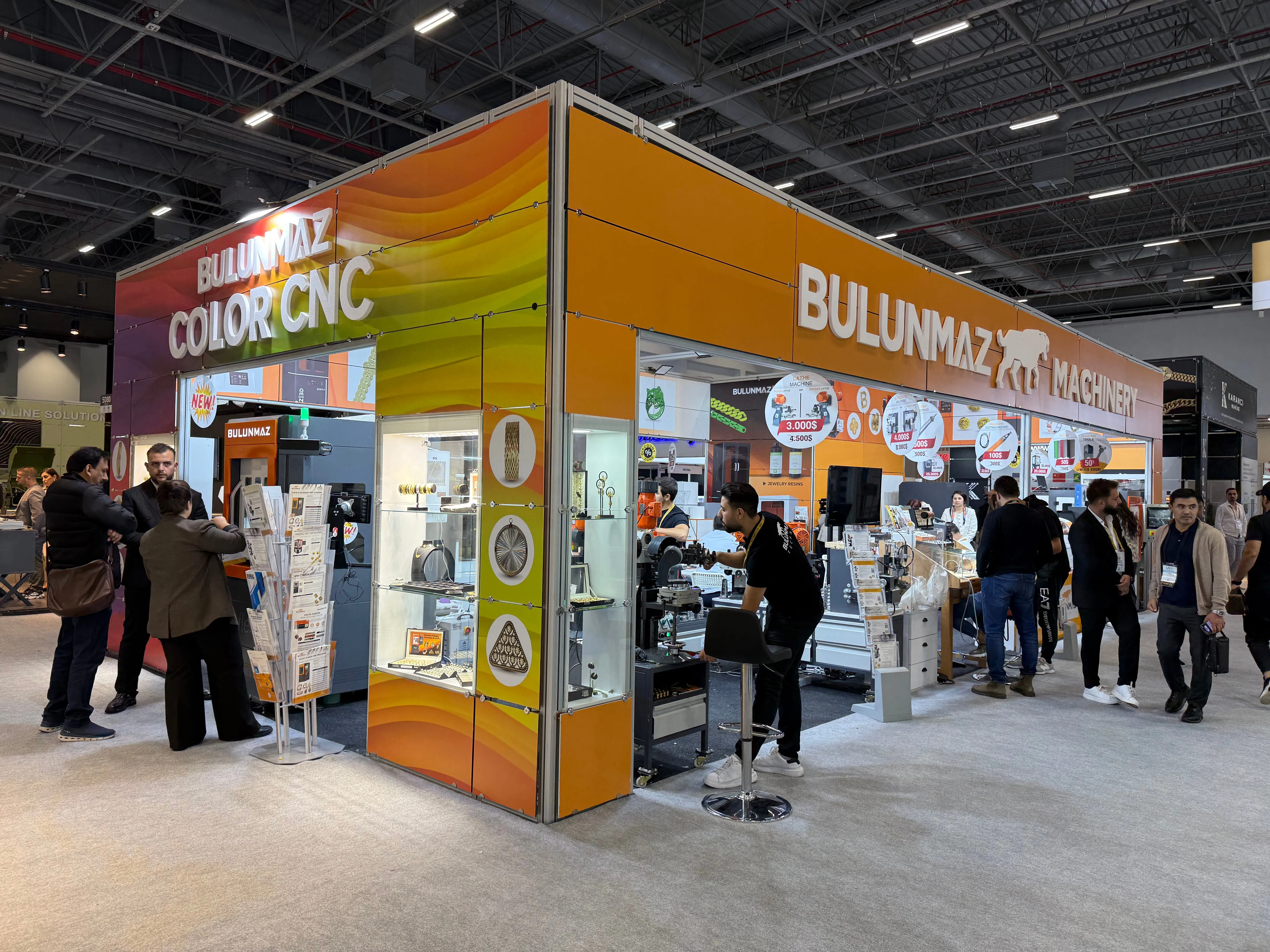 Colorful Bulunmaz Machinery trade show booth with people interacting and machinery displayed inside.