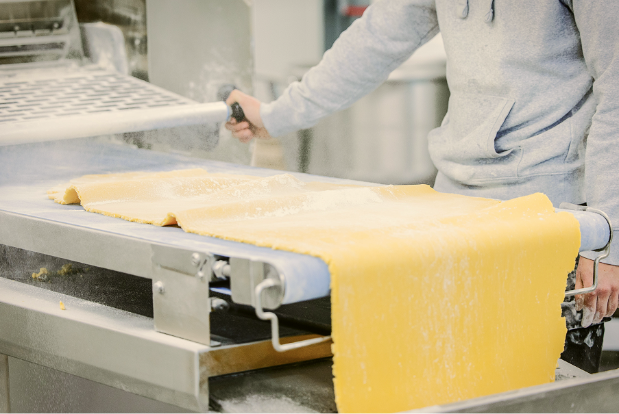 Zanddeeg wordt uitgerold door een medewerker van Sablé Breton op de productielijn