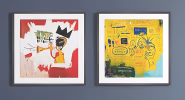 Two framed abstract artworks on a blue wall featuring vivid colors and graffiti-like elements.
