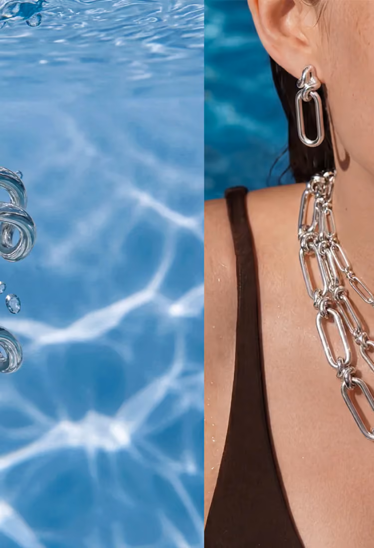 Close-up of a person wearing chunky silver chain-link earrings and necklace, with water and bubbles visible on the left side.
