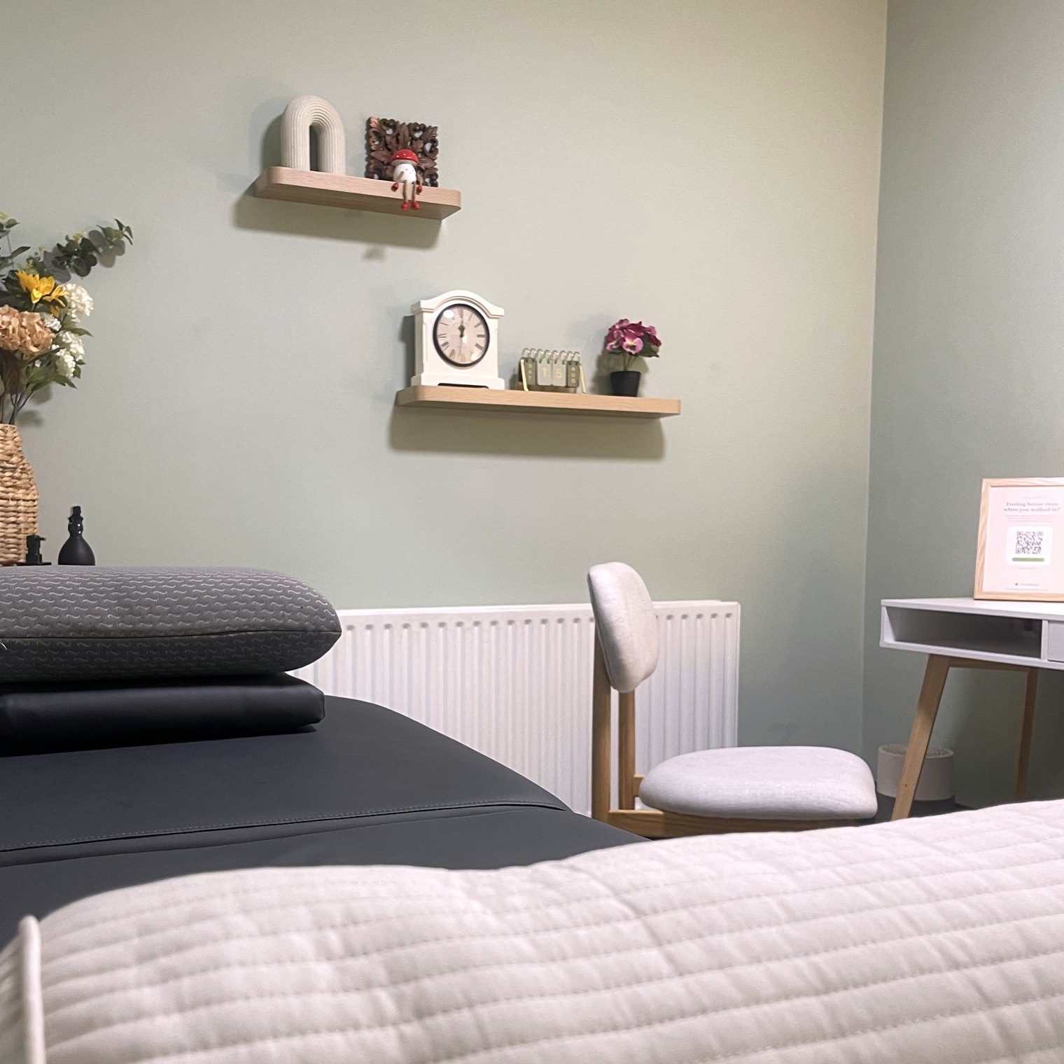 Treatment room at TandemBalance, Cork, seen from the massage plinth, with cream bolster, pillows and sage green wall