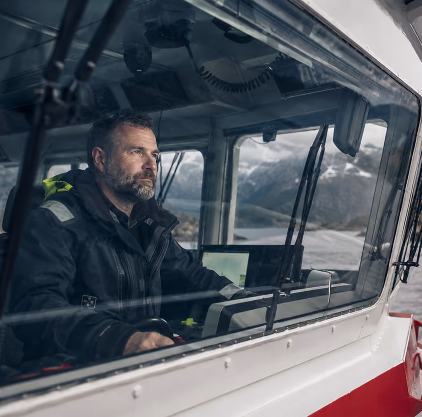 En skipsfører styrer et Abyss-fartøy gjennom en norsk fjord.