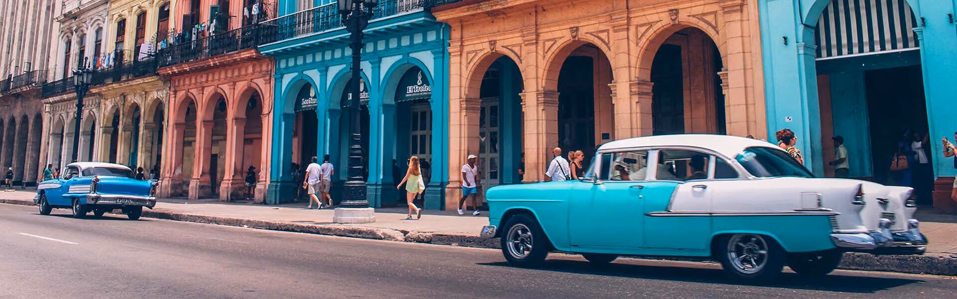 A busy city street with colourful buildings and a blue car