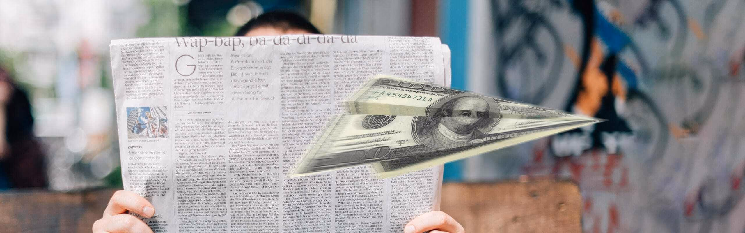 A paper airplane being thrown infront of someone reading a newspaper