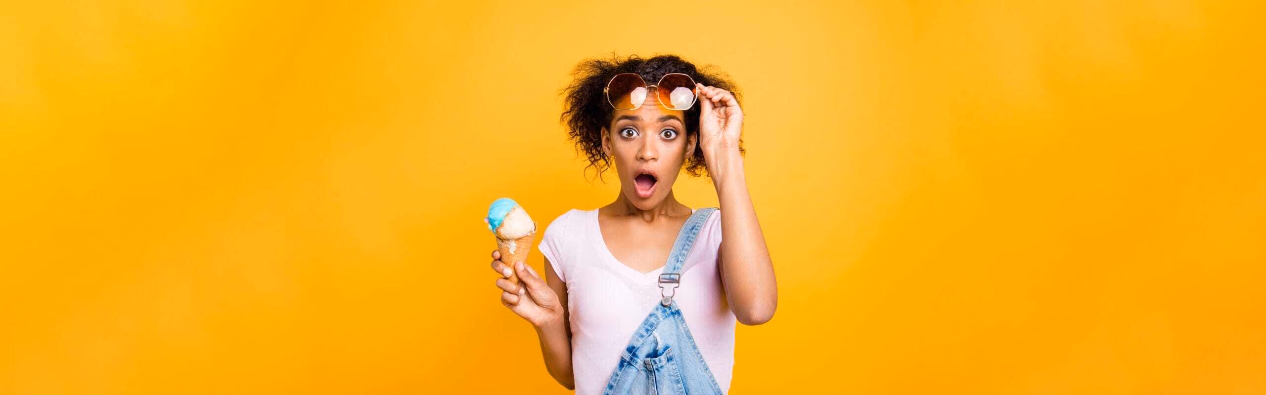 A person holding an ice cream against a yellow background