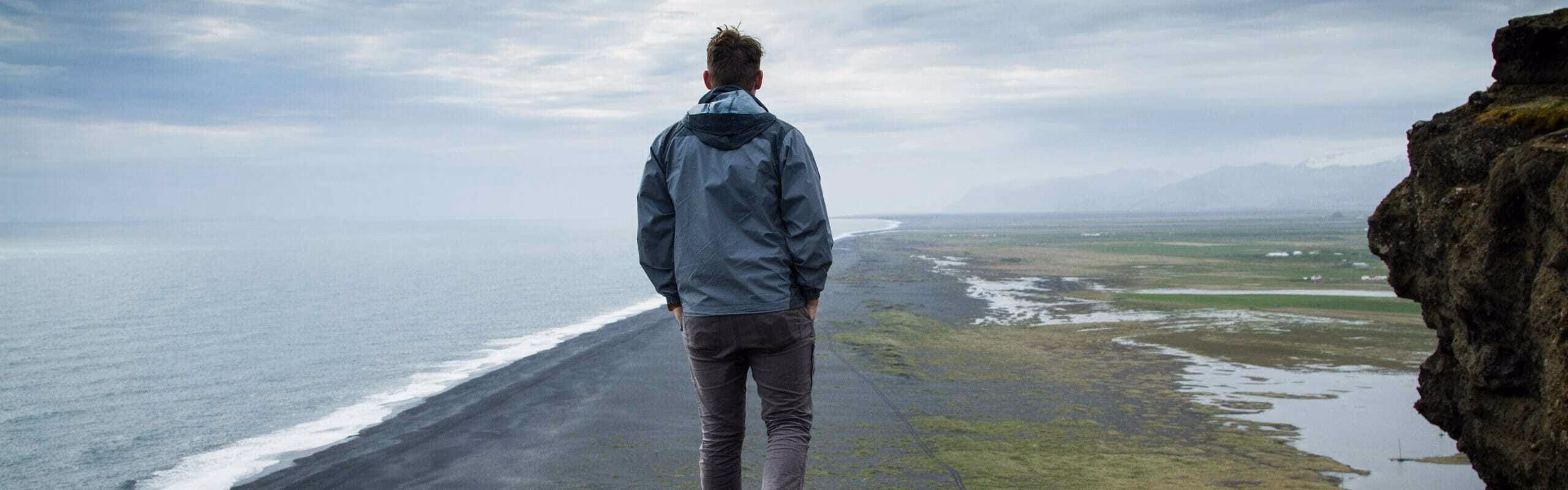 shot of a man walking along the coast from behind