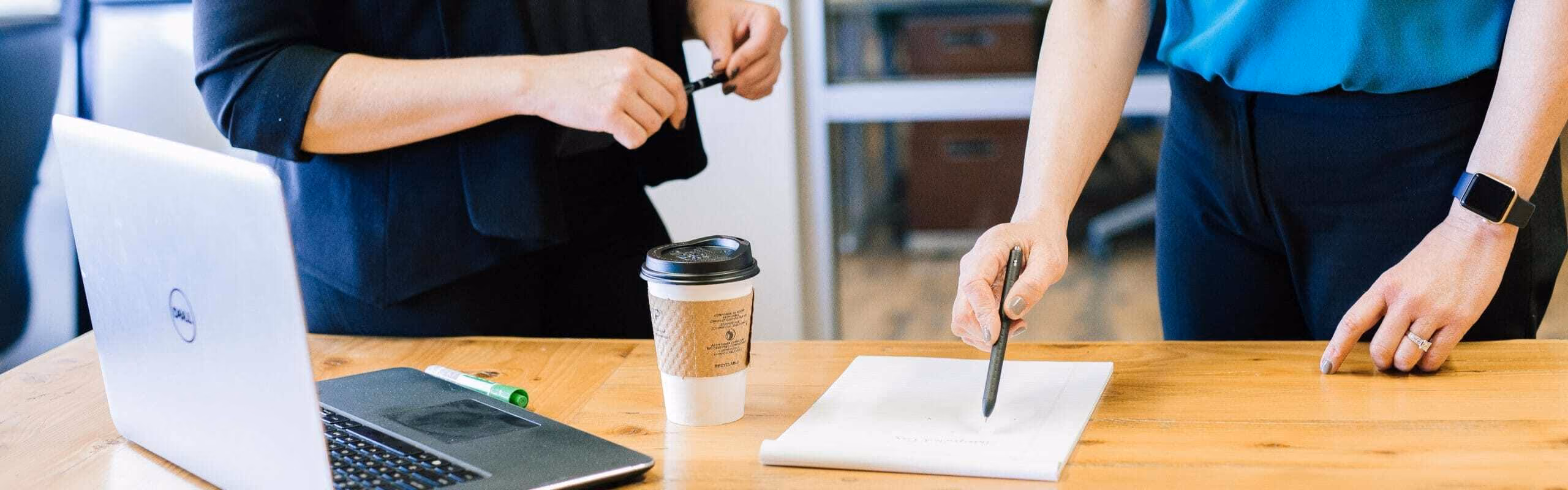 People working with one of them pointing at a paper pad with a pen