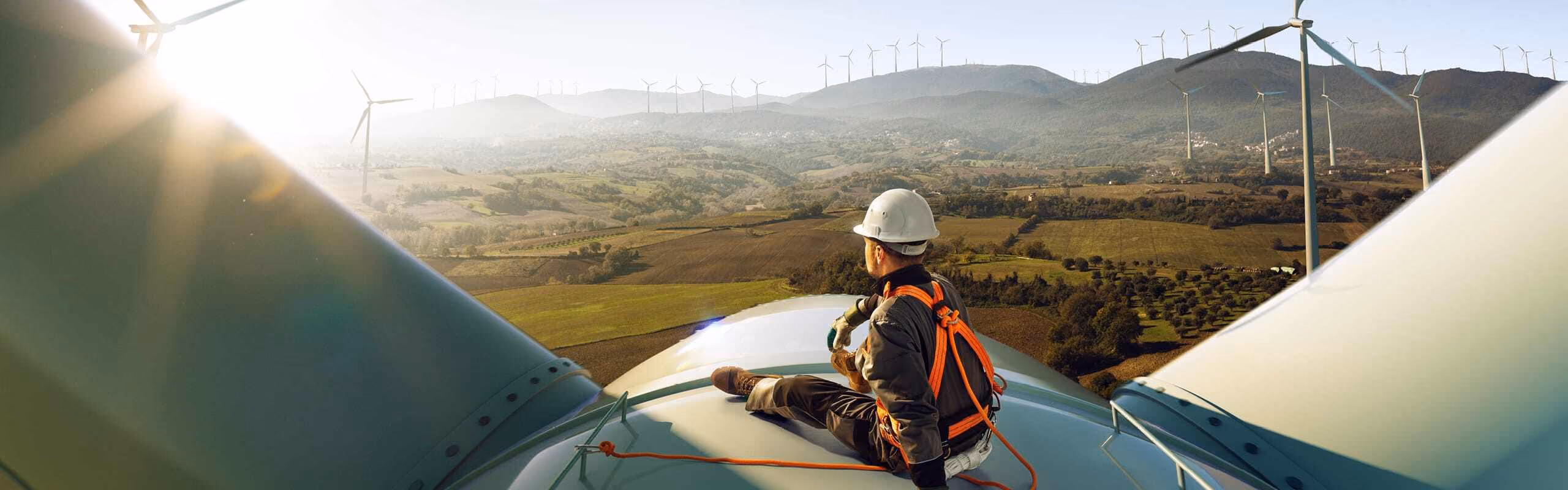 A person sitting on top of a wind turbine