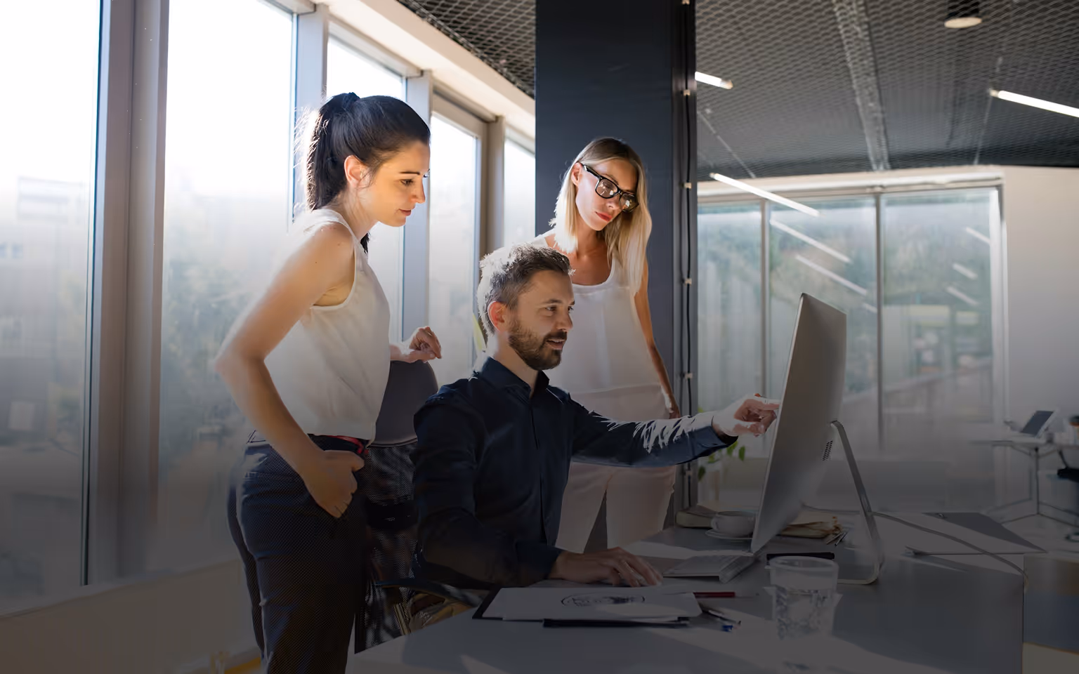 Drei Personen bei der Arbeit an einem Computer in einem hellen modernen Büro.