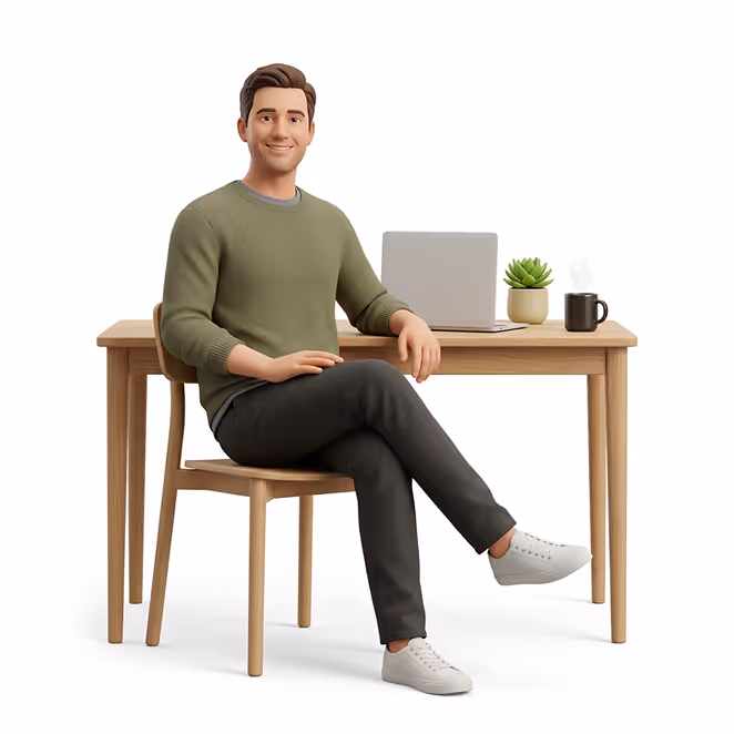 Ein Mann sitzt mit verschänkten Beinen an einem Holztisch mit Laptop, Pflanze und Kaffeetasse.