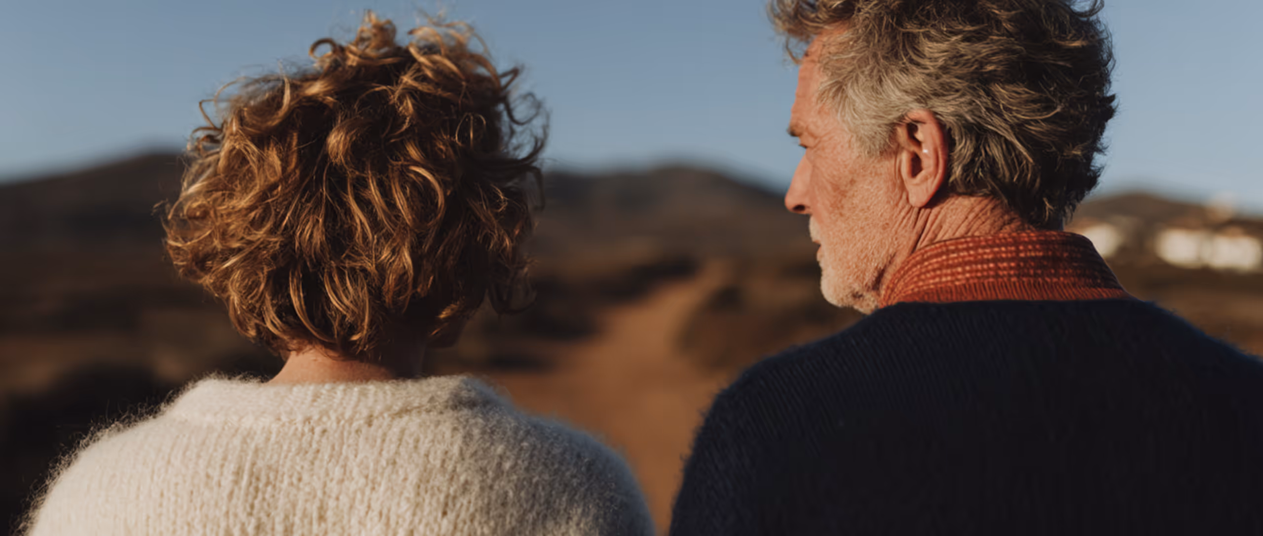 Vue arrière d'un homme et d'une femme âgés regardant un sentier en plein air au coucher du soleil.
