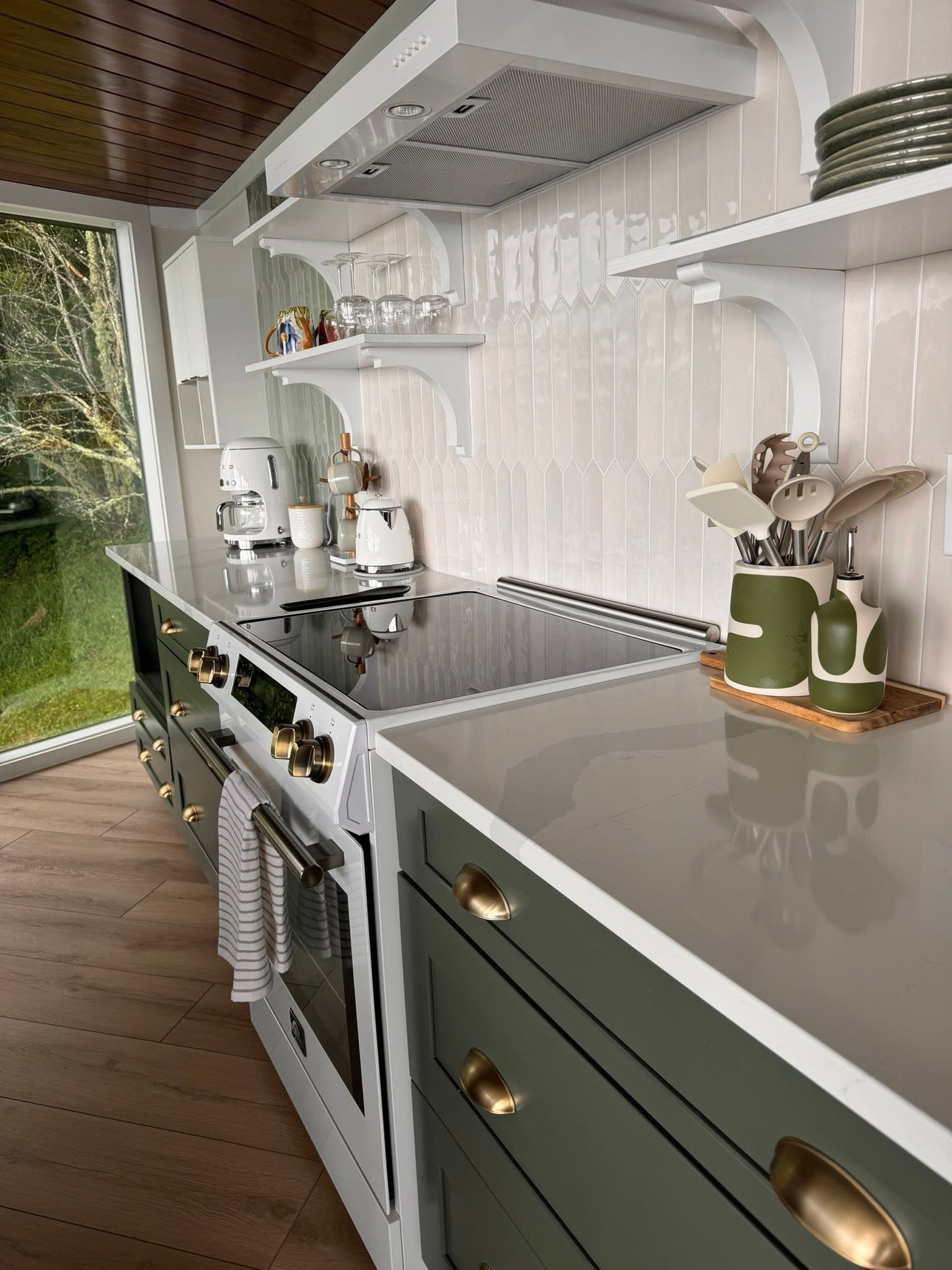 Fully equipped modern kitchen with green cabinetry and brass hardware in a short-term rental listing