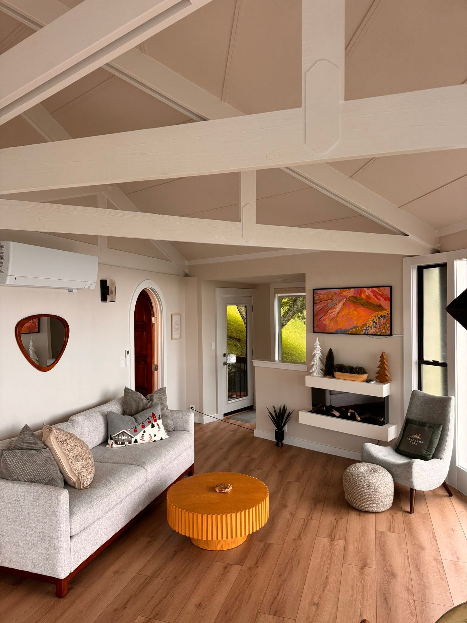 Welcoming open-plan living room with a vaulted, beamed ceiling and mountain-cabin styling in a managed short-term rental
