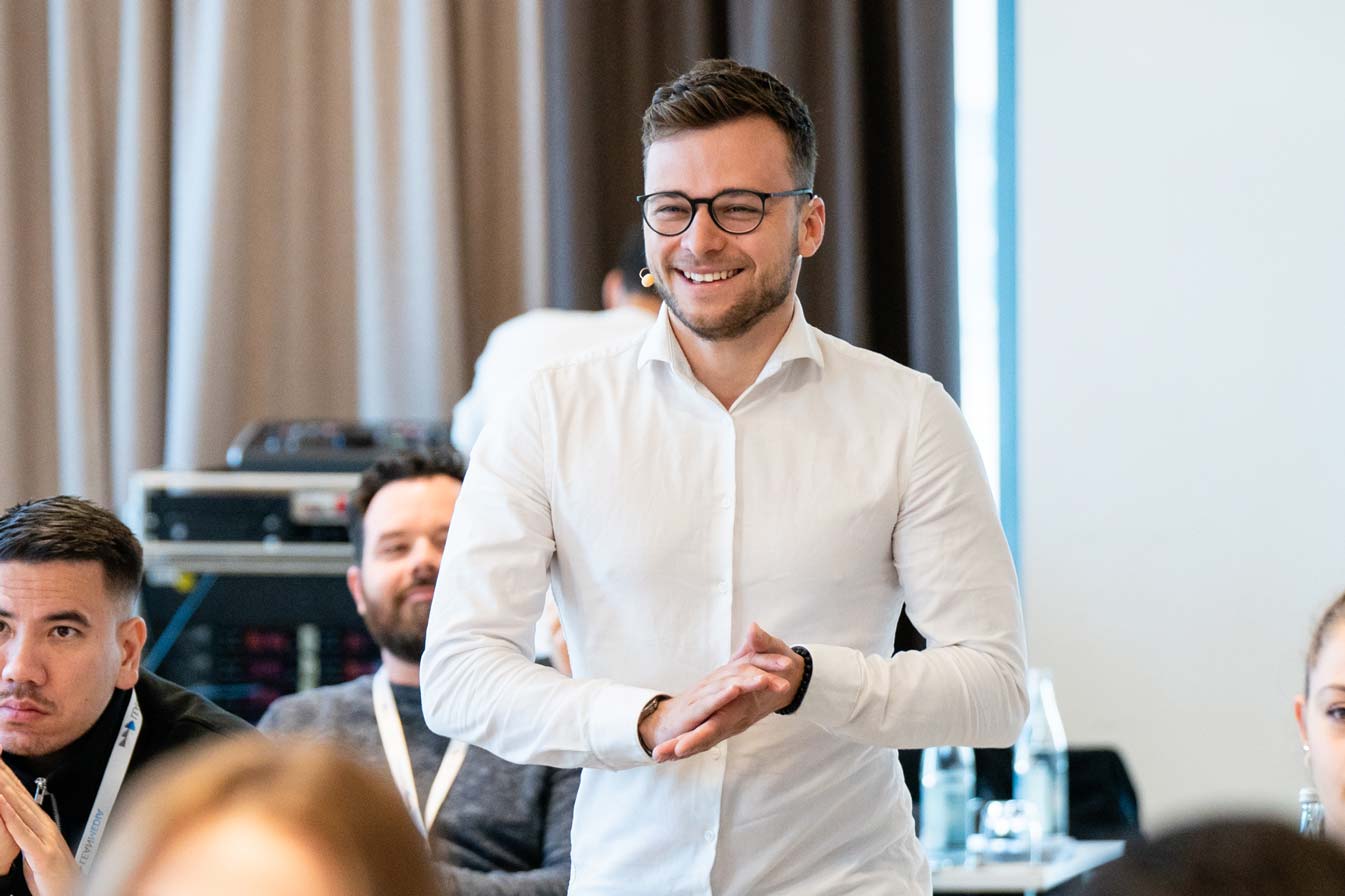 Paul Gerngross, der in der Webdesign Agentur in Erlangen arbeitet, trägt ein weißes Hemd und lacht.