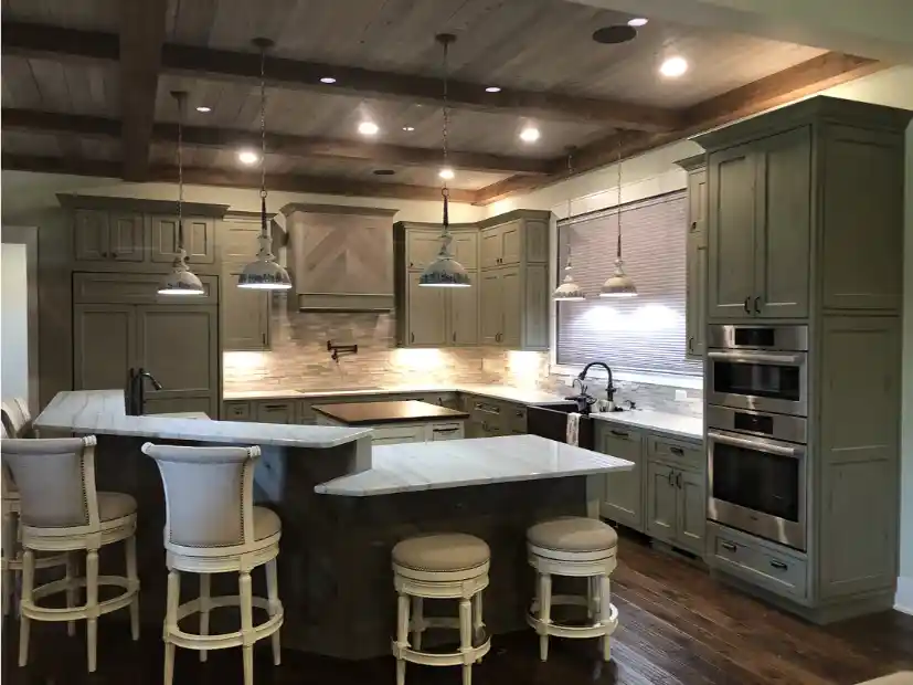 Modern kitchen with olive green cabinets, marble countertops, wooden ceiling, and bar stools.