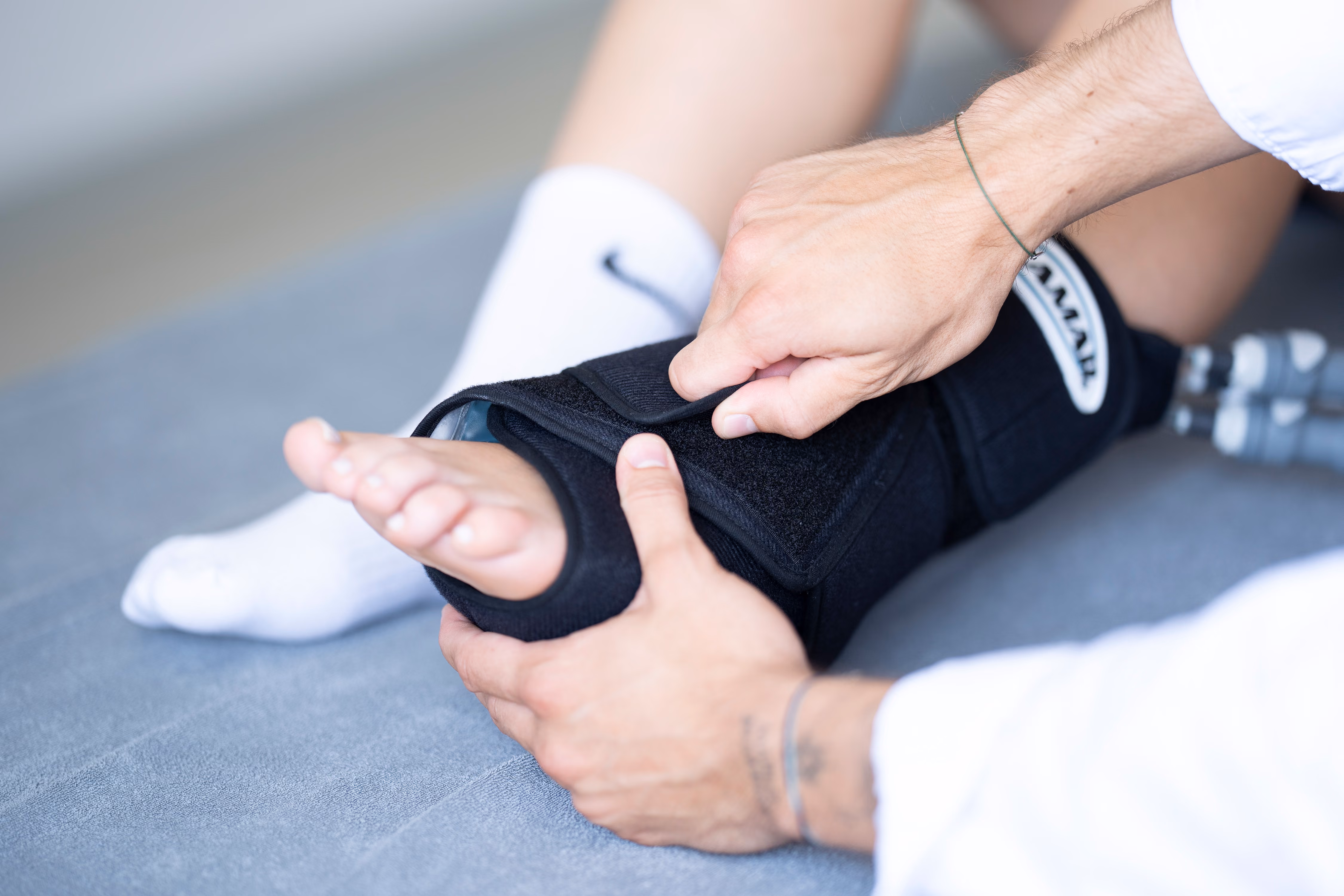 Person adjusting a black brace on a foot with a prosthetic leg visible.