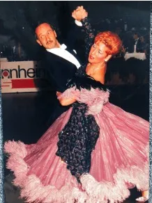 Tanzpaar in eleganten Kleidern bei einem Ball, Frau trägt ein rosa Kleid mit schwarzen Akzenten.