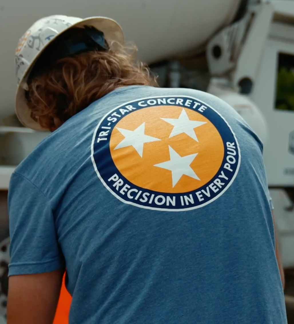 Back view of worker's shirt with Tri-Star Concrete logo, suggesting construction work.